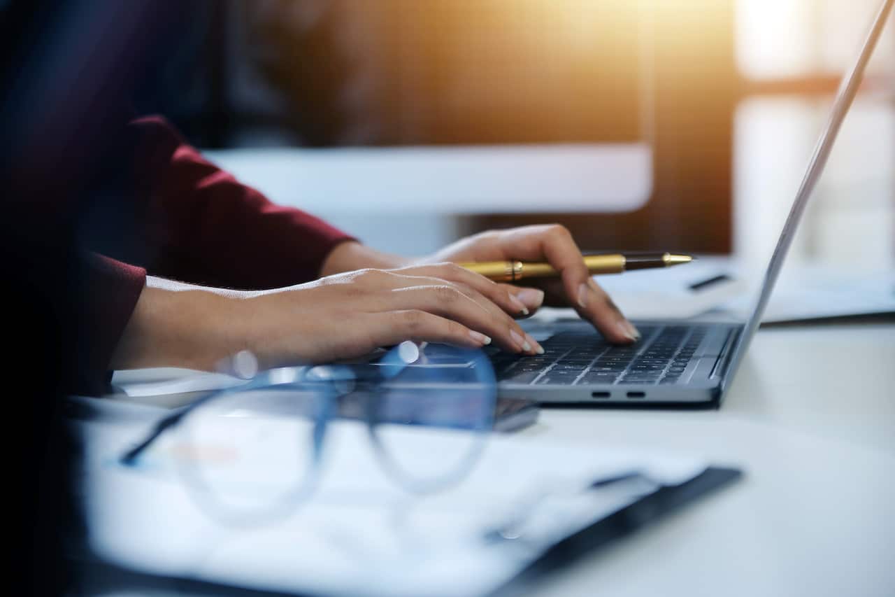 Cropped image of professional businesswoman working at her office via laptop, young female manager using portable computer device while sitting at modern loft, flare light, work process concept